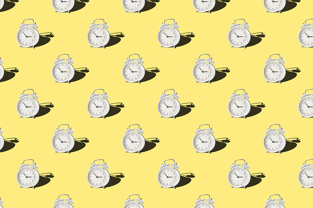 clocks in a repeating pattern against a yellow background